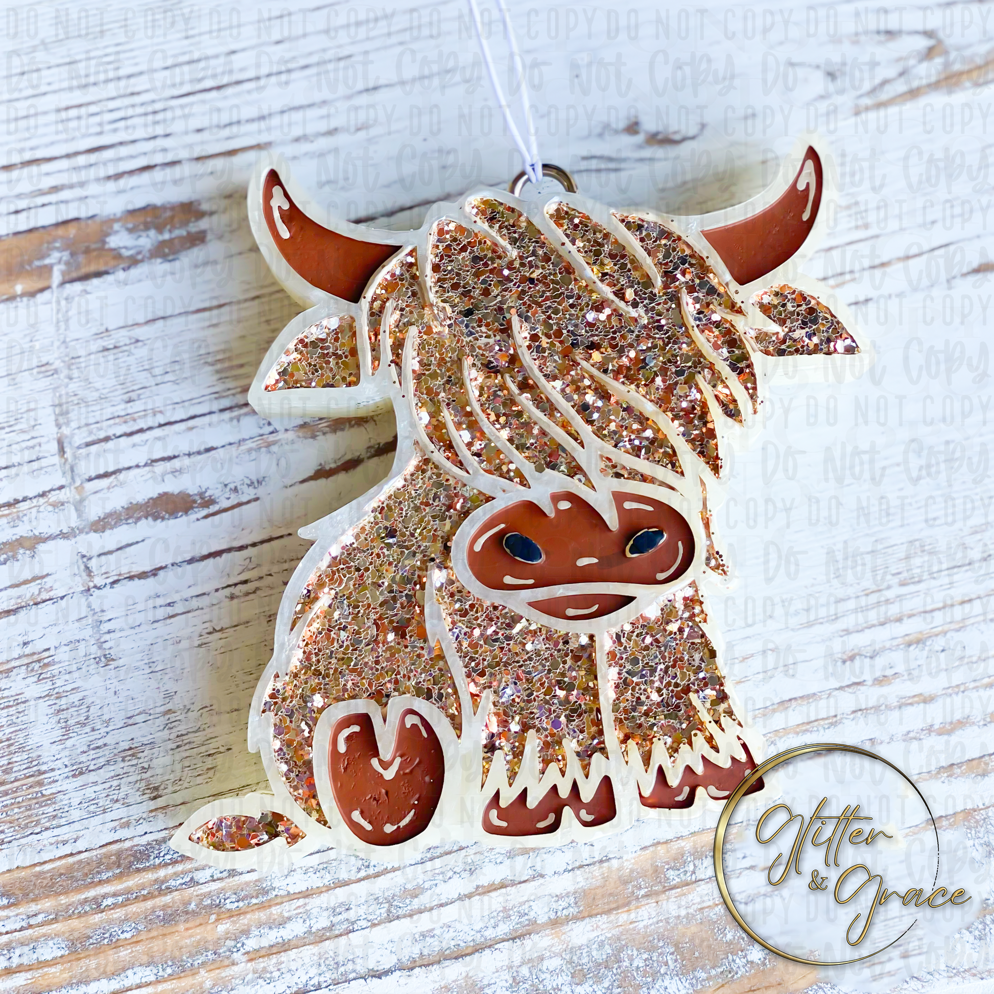 car air freshener in the shape of a highland cow decorated with light browns and golden glitter