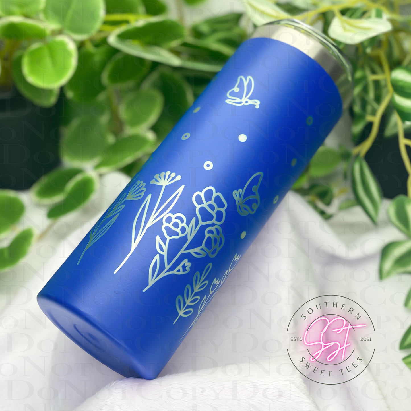 20oz skinny powder coated tumbler in blue laser engraved with florals and butterflies all the way around the tumbler