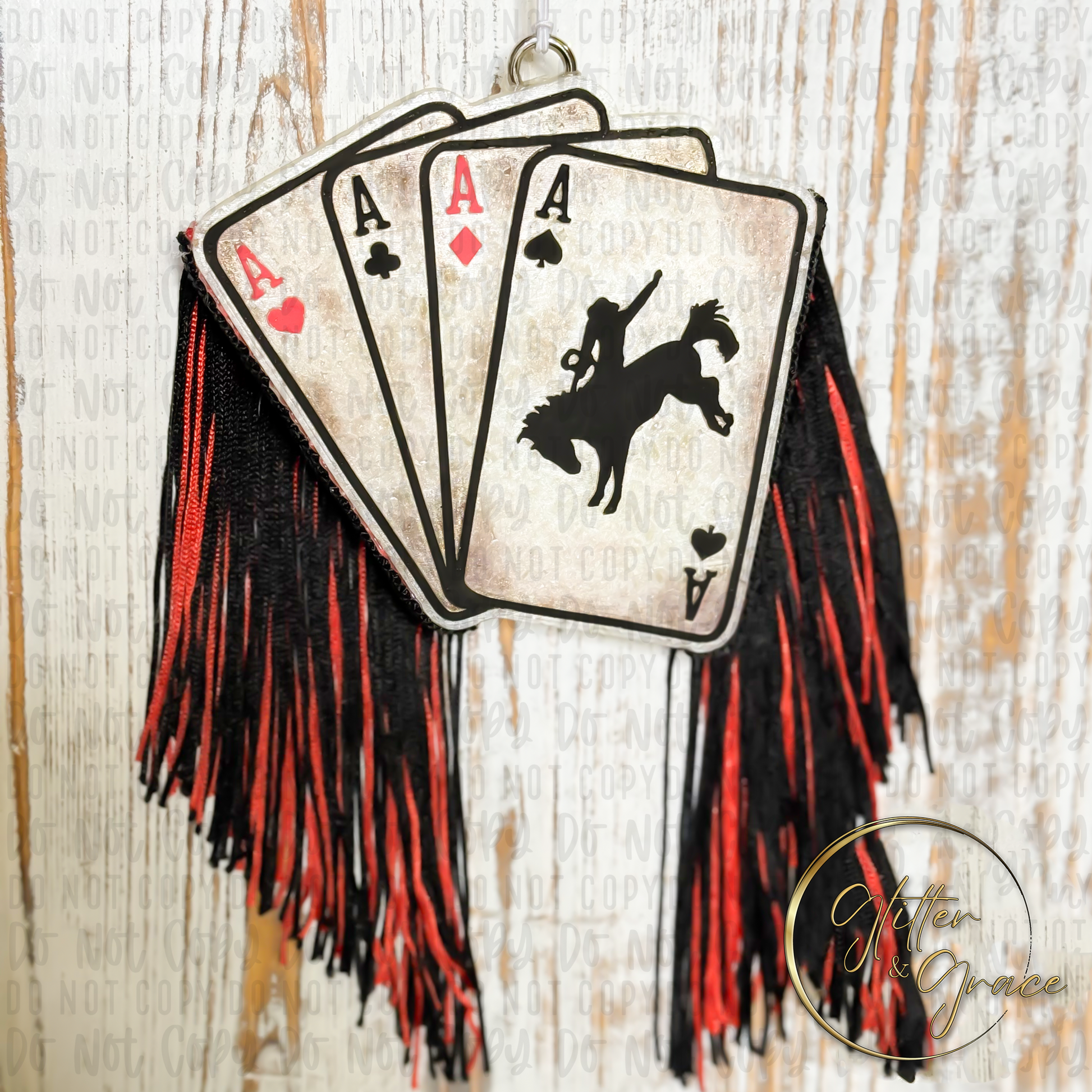 vehicle air freshener shaped as playing cards with all the Aces and a cowboy with red and black fringe in a grunge look and feel