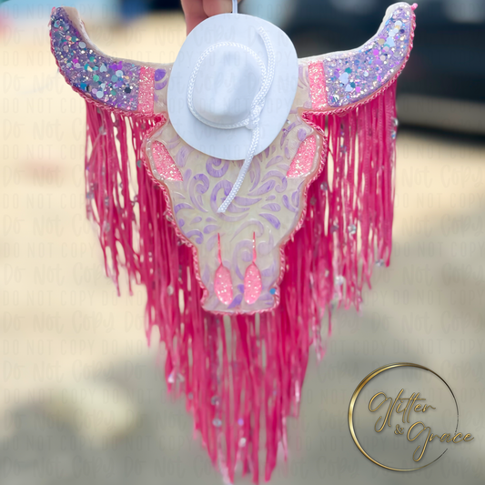 vehicle air freshener shaped as a bull decorated with lace cowboy hat and fringe